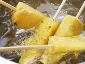 パイナップルを割り箸に刺したら氷水に入れて冷やす
